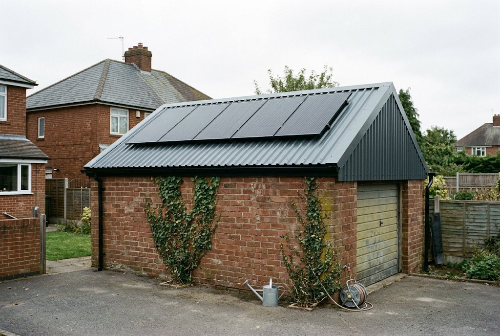 Brick garage with a new deeply corrugated grey steel roof and solar panels